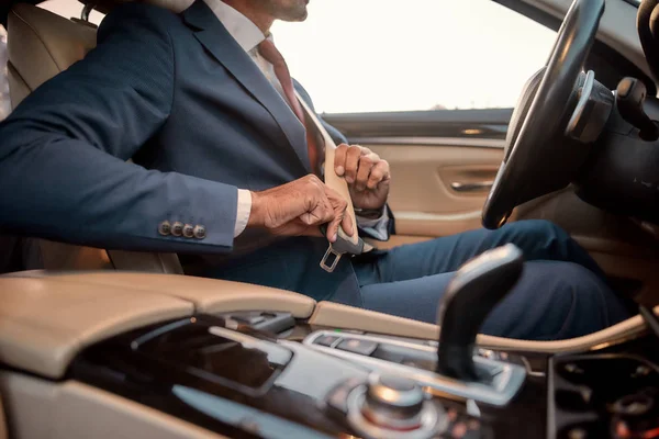 Conducción segura. Foto recortada de un hombre de negocios en traje completo sentado en el asiento del coche y la fijación del cinturón de seguridad — Foto de Stock