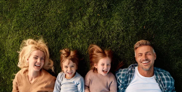 Familjesemester. Lycklig familj på fyra ligger på grönt gräs — Stockfoto