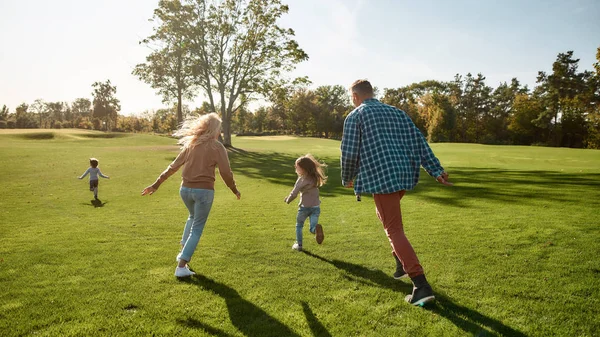 Börjar bli kul. Spännande familj springer utomhus på en solig dag — Stockfoto
