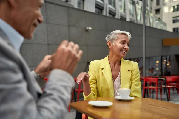 Entspannung bei einer Tasse frischem Kaffee. glückliches älteres Paar genießt Kaffee und lächelt, während es auf der Café-Terrasse sitzt — Stockfoto