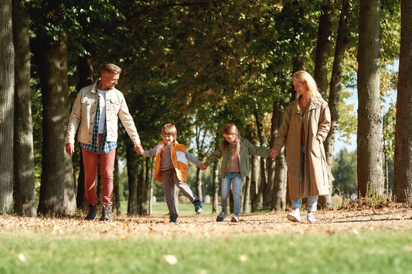 Parents et enfants. Joyeux famille tenant la main et marchant dans le parc — Photo