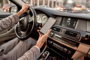 Modern teknolojileri kullanarak. Araba kullanırken akıllı telefonunu tutan bir kadının kesilmiş fotoğrafı..