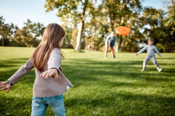 Aquí vamos de nuevo. Niña jugando frisbee con su familia en el parque en un día soleado — Foto de Stock