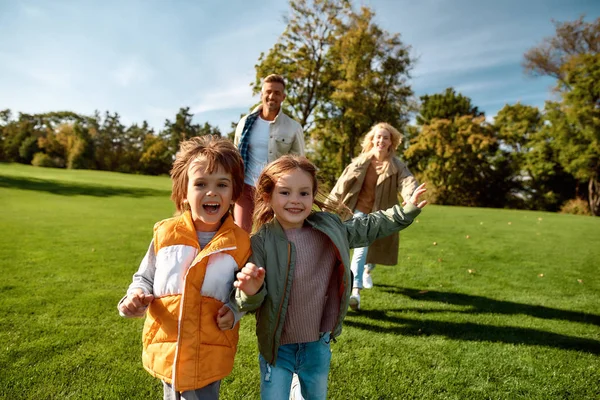 Solig helg. Spännande familj springer utomhus på en solig dag — Stockfoto