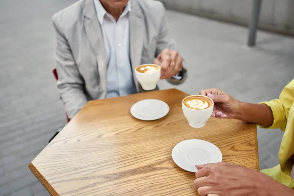 Meeting with a good friend. Cropped photo of stylish people drinking coffee in a cafe outdoors — 图库照片