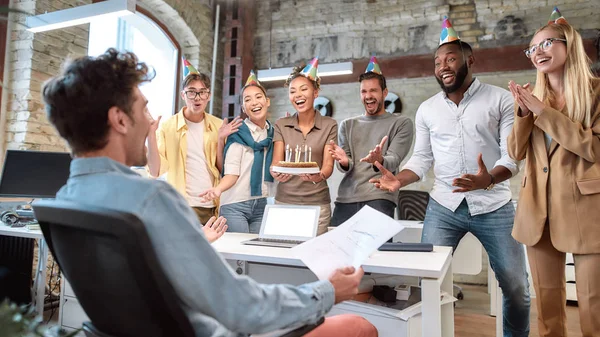 Itt az ideje ünnepelni. Vegyes faj boldog fiatal munkatársak ünnepli születésnapját kollégája a modern irodában — Stock Fotó