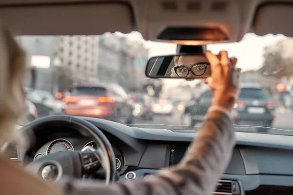 Jedź ostrożnie. Piękna kobieta biznesu siedząca na przednim siedzeniu samochodu i regulująca lusterko wsteczne — Zdjęcie stockowe