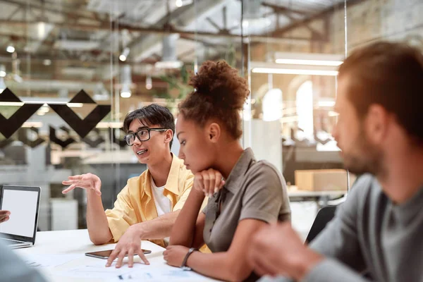 Multikulturellt team. Grupp unga affärsmän diskuterar något med sina unga kollegor samtidigt som de arbetar tillsammans på det moderna kontoret — Stockfoto