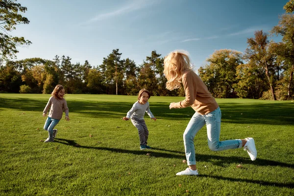 Ευτυχισμένα παιδιά, ανέμελοι γονείς. Ενθουσιασμένη οικογένεια τρέχει έξω σε μια ηλιόλουστη μέρα — Φωτογραφία Αρχείου