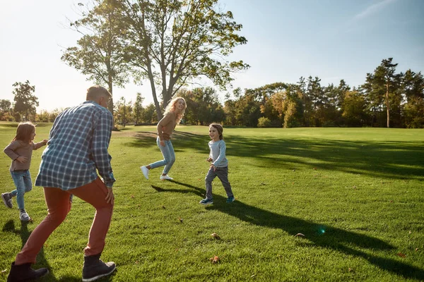 Des parents dévoués. Famille excitée courir à l'extérieur par une journée ensoleillée — Photo