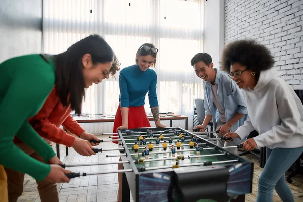 Mutlu takım. Bir grup genç ve çok kültürlü insan modern ofiste masa futbolu oynayıp gülüyorlar. Ofis aktiviteleri. Birlikte eğleniyoruz. Mutlu çalışanlar — Stok fotoğraf