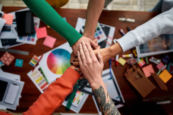 Building success together. Group of multicultural creative people stacking hands over the desk with graphic designers work tools and equipment on it. Web design concept. Teamwork — Stock Photo, Image