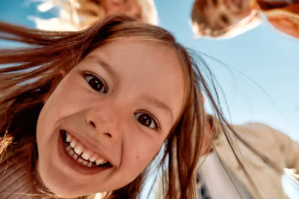 El mejor día de mi vida. Vista inferior de la niña feliz y linda sonriendo a la cámara mientras pasa tiempo con su familia al aire libre — Foto de Stock