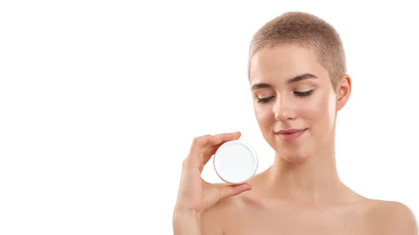 Testing daily cream. Young attractive blonde woman with short haircut demonstrating cosmetic product while standing in studio against white background — Stock Photo, Image