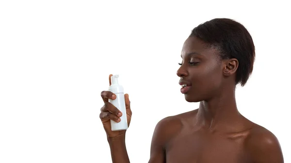 Hogy tiszta és friss legyen a bőre. Portré gyönyörű fiatal afrikai nő bemutató kozmetikai termék és a kamera, miközben áll a stúdióban, fehér háttér — Stock Fotó