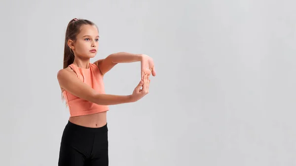 Tutti nella vita hanno bisogno di equilibrio. Flessibile bambina carina guardando da parte mentre stende le mani isolate su uno sfondo bianco. Sport, fitness, stile di vita attivo. Colpo orizzontale . — Foto Stock