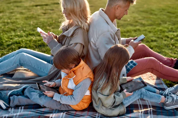 Geteilt durch Technologien. Familie verbringt an einem sonnigen Tag Zeit im Park — Stockfoto