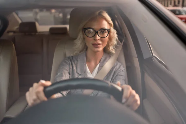 Adoro conduzir o meu carro. Retrato de atraente jovem mulher de negócios em óculos sorrindo enquanto dirige um carro — Fotografia de Stock