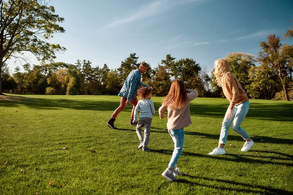 Vilar tillsammans. Spännande familj springer utomhus på en solig dag — Stockfoto
