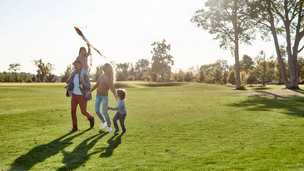 The first happiness of a child to know that he is loved. Happy family playing a kite. Outdoor family weekend — 스톡 사진