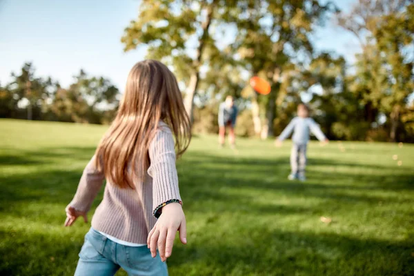 Det finns ingen bättre gåva än en familj. Liten flicka som leker frisbee med sin familj i parken på en solig dag — Stockfoto