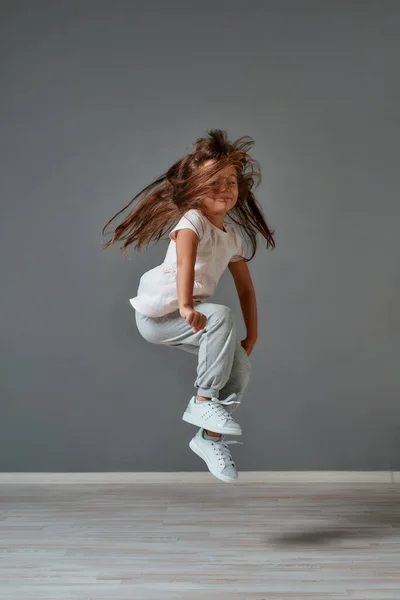 장난기있는 기분. 단발의 옷을 입고 스튜디오에서 점프하는 귀엽고 흥분 한 어린 소녀의 사진. 행복 한 아이들 — 스톡 사진