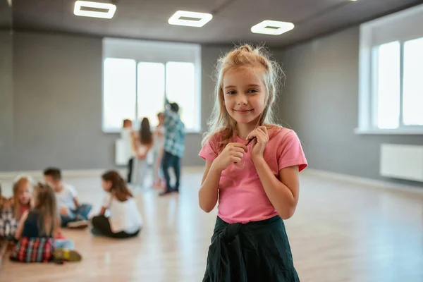 Tempo di relax. Ritratto di una bambina felice che guarda la macchina fotografica e sorride in piedi nello studio di danza. Lezione di coreografia — Foto Stock