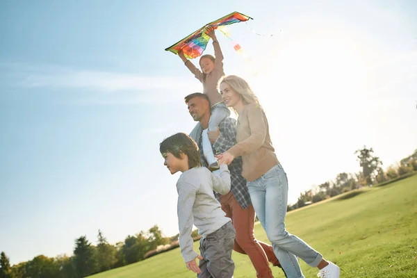 Laissez vos enfants déployer les ailes. Joyeux famille jouant au cerf-volant. Week-end familial extérieur — Photo