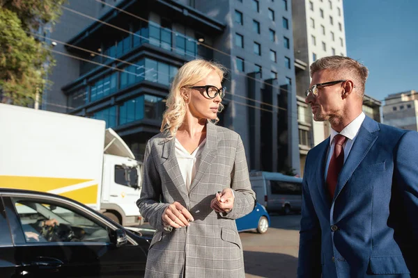 Nieuwe zakelijke ideeën delen. Twee succesvolle zakenmensen praten over iets terwijl ze samen buiten staan tegen glas business center — Stockfoto