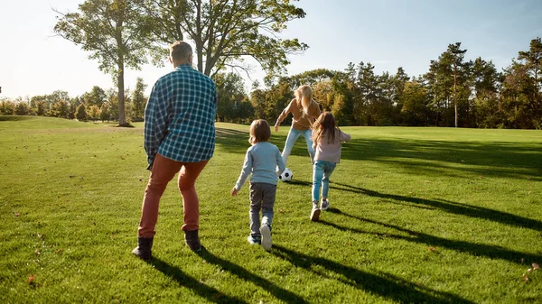 Meleg és szeretetteljes környezet. Boldog család játszik a labdával a mezőn — Stock Fotó