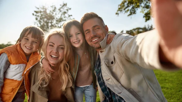 Todo el mundo está sonriendo ahora mismo. Familia feliz tomando selfies al aire libre —  Fotos de Stock