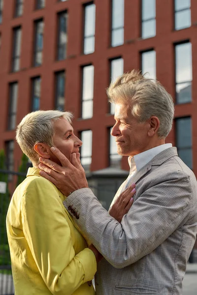 美しい目だ。一緒に屋外に立っている間、お互いを見てスーツジャケットでロマンチックな成熟したカップルの肖像画 — ストック写真