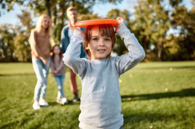 Çocuklar çiçekler gibidir. Küçük çocuk güneşli bir günde parkta frizbi oynuyor.