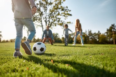 Biraz futbol oynamaya hazır mısın? Mutlu aile çayırda top oynuyor.
