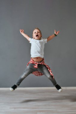Happy childhood. Full length portrait of excited little boy in casual clothes jumping and screaming in studio