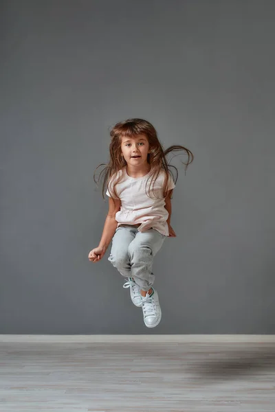 Happy childhood. Portrait of a cute and excited little girl in casual clothes jumping in studio — Stockfoto