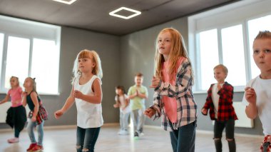 Love to move. Group of cute and active children in casual clothes learning a modern dance in the dance studio. Choreography class. Activity. Hobby