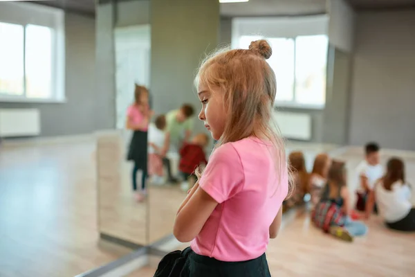 Sto pensando a qualcosa. Vista posteriore di una bambina carina che guarda altrove e sogna mentre si trova in studio di danza. Gruppo di bambini con un corso di coreografia. Attività. Scuola di danza — Foto Stock