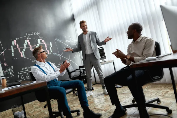 Excelentes maestros para una excelente educación. De larga duración de los empleados diversos, comerciantes discutiendo la estrategia de trabajo, mientras que escuchar a colega de pie cerca de pizarra. Disparo horizontal —  Fotos de Stock