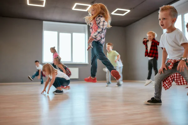 Más alto. Niños saltando mientras tienen una clase de coreografía. Grupo de niños y niñas lindos estudiando danza moderna en el estudio —  Fotos de Stock