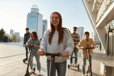 Saatte daha fazla gülümseme. Güneşli bir günde scooter ve segway kullanan bir grup arkadaş.