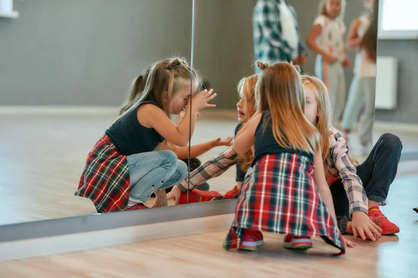 A fazer uma pausa. Grupo de meninas bonitos e na moda conversando enquanto sentado no chão perto do espelho no estúdio de dança. Classe de coreografia — Fotografia de Stock
