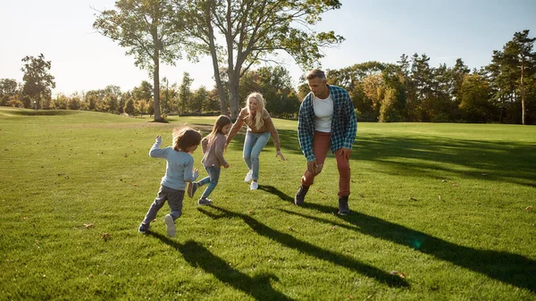 Ebeveynlerin dinlenmesine yardım etmek. Güneşli bir günde dışarıya koşan heyecanlı bir aile. — Stok fotoğraf