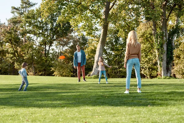 C'est le week-end. Bon appétit. Les parents jouent au frisbee avec leurs enfants dans le parc par une journée ensoleillée — Photo