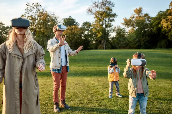 Una forma innovadora. Familia de cuatro jugando en gafas de realidad virtual al aire libre —  Fotos de Stock