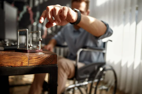 Newtons wieg. Gehakte wazige foto van een zakenman in een rolstoel die Newton ballen verplaatste terwijl hij op zijn werk op kantoor zat. Arbeidsongeschikte kantoormedewerker — Stockfoto