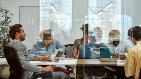 Fissare gli obiettivi. Gruppo di uomini d'affari che comunicano e discutono idee fresche seduti insieme dietro la parete di vetro nella sala riunioni — Foto Stock