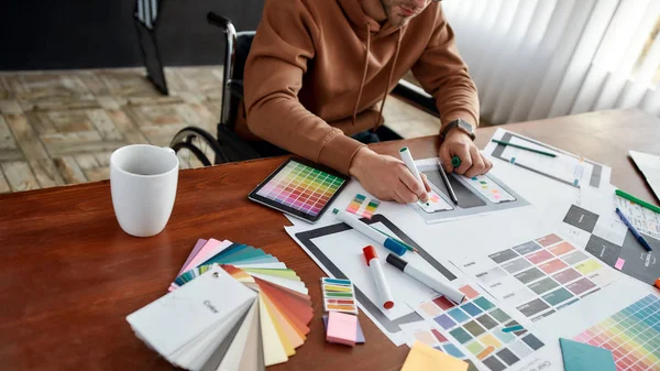 Zugeschnittenes Foto eines männlichen UX-Designers im Rollstuhl, der an seinem kreativen Arbeitsplatz im modernen Büro sitzt und eine neue mobile App entwirft — Stockfoto