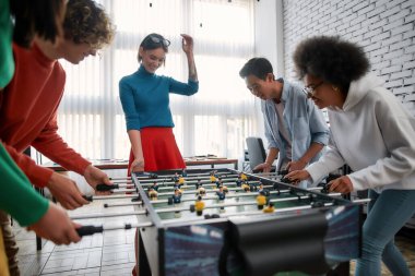 Eğlenceli takım kurma oyunları. Bir grup genç ve mutlu çok kültürlü insan yaratıcı ofiste masa futbolu oynuyor. Ofis aktiviteleri. Birlikte eğleniyoruz. Mutlu çalışanlar