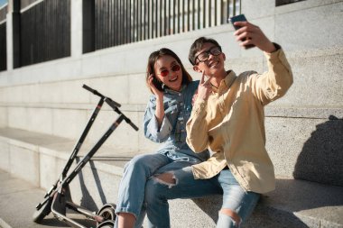 Anı yakalamak. Güneşli bir günde elektrikli scooter süren arkadaşlar.